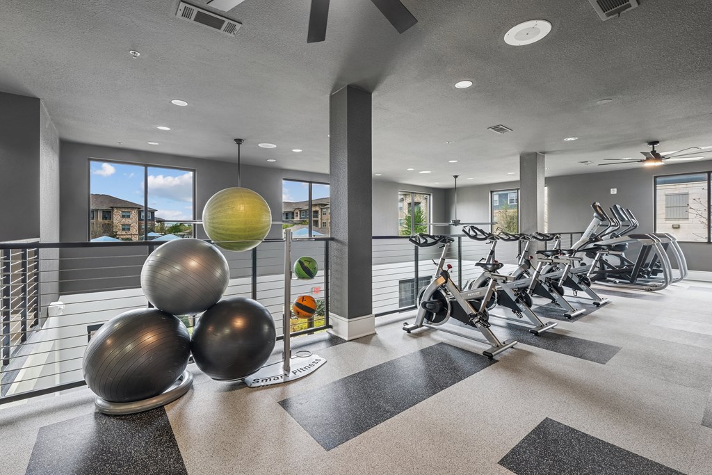 A gym with a row of exercise bikes and a yellow hanging light fixture.