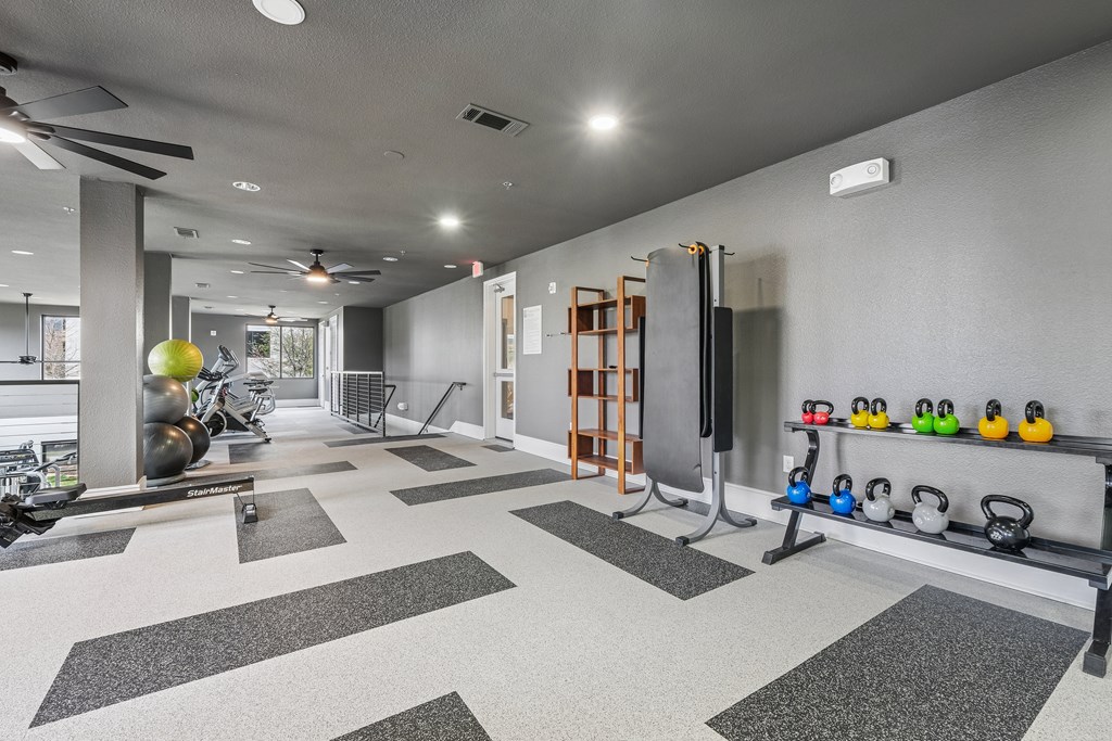 A spacious gym with a variety of equipment including a squat rack, kettlebells, and a bench press.