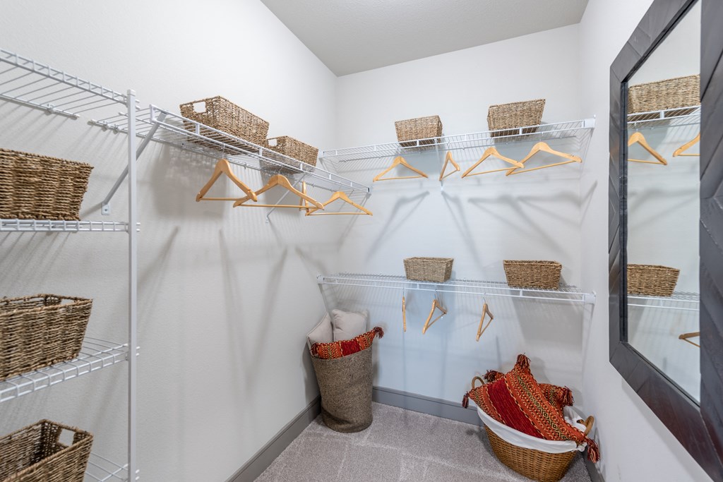 a walk in closet with white walls and wicker baskets