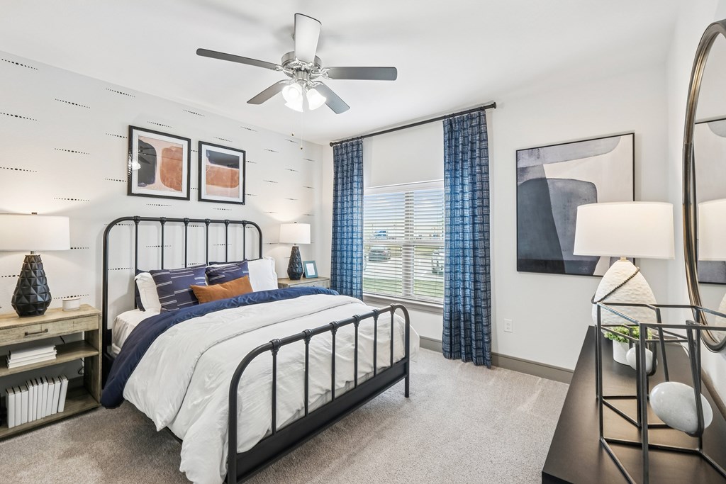 A bedroom with a bed, nightstand, and a ceiling fan.
