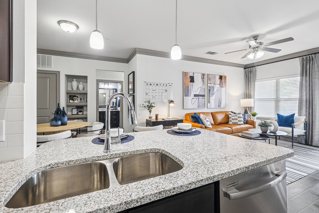 A modern kitchen with a granite countertop and stainless steel sink.