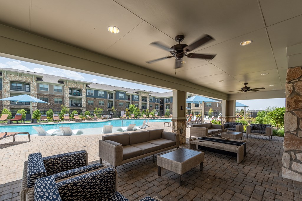 a resident clubhouse with a pool and lounge area with couches and chairs