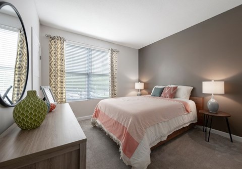 A bedroom with a bed, nightstand, and a mirror.