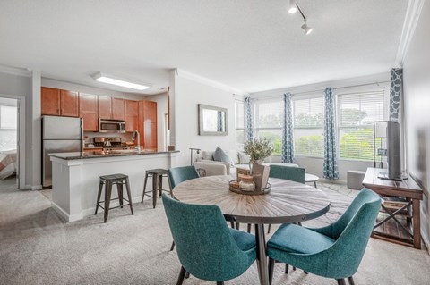 A modern dining room with a round table and green chairs.