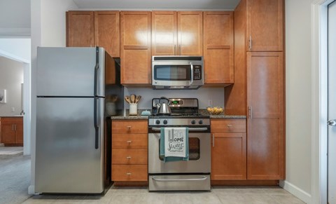 A kitchen with a stainless steel refrigerator, a microwave, and a stove with a sign on it.