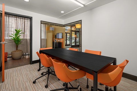 A conference room with a long table and orange chairs.