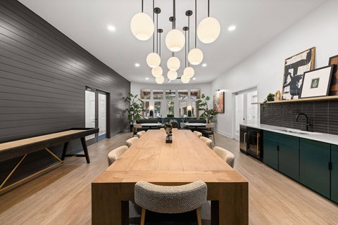 A modern dining room with a long wooden table and chairs.