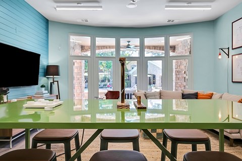 A dining room with a green table and chairs.