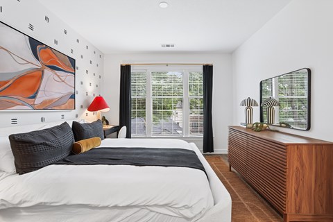 A bedroom with a large bed and a painting on the wall.