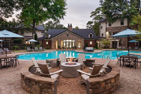 A backyard with a fire pit and chairs around a pool.