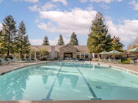 a swimming pool with chairs and a building in the background