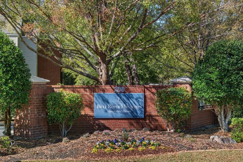 a sign in front of a brick wall with trees in the background