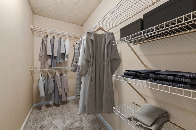 a spacious walk in closet with white walls and a beige carpet