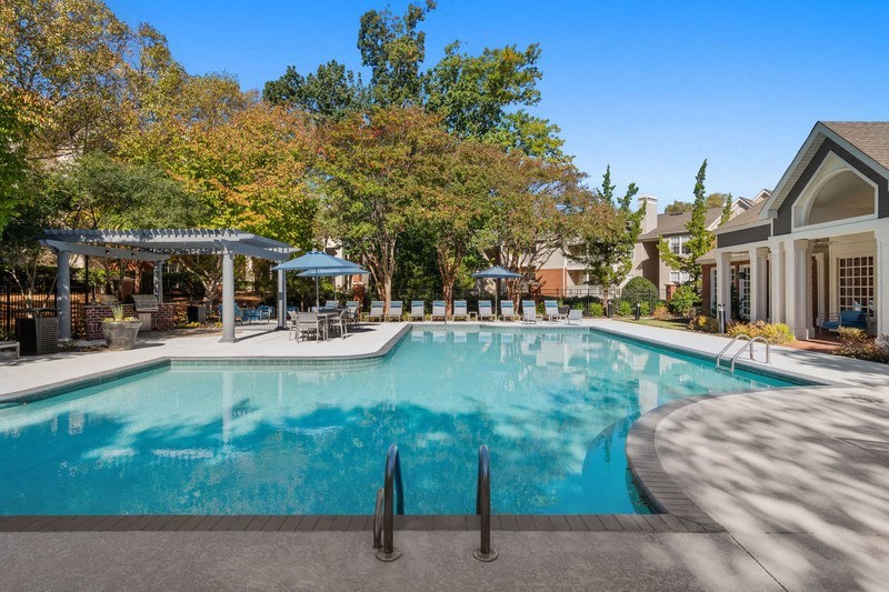 a swimming pool with umbrellas and a house in the background