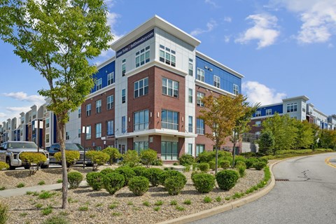 A modern multi-story building with a parking lot in front.
