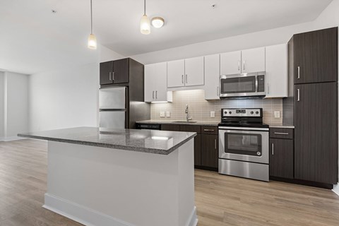 A modern kitchen with dark brown cabinets and stainless steel appliances.