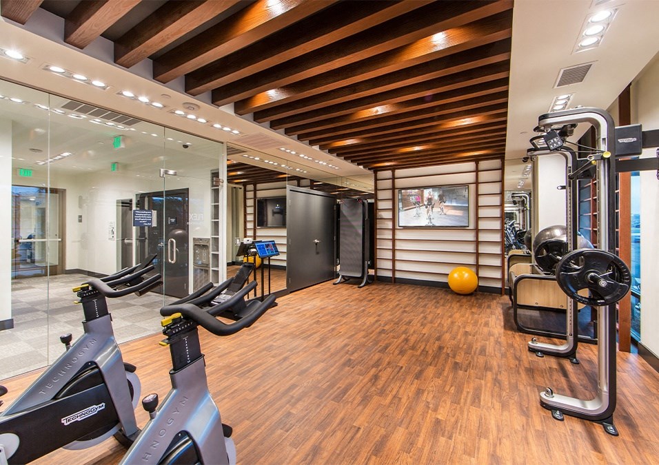 a gym with treadmills and other exercise equipment on a wooden floor