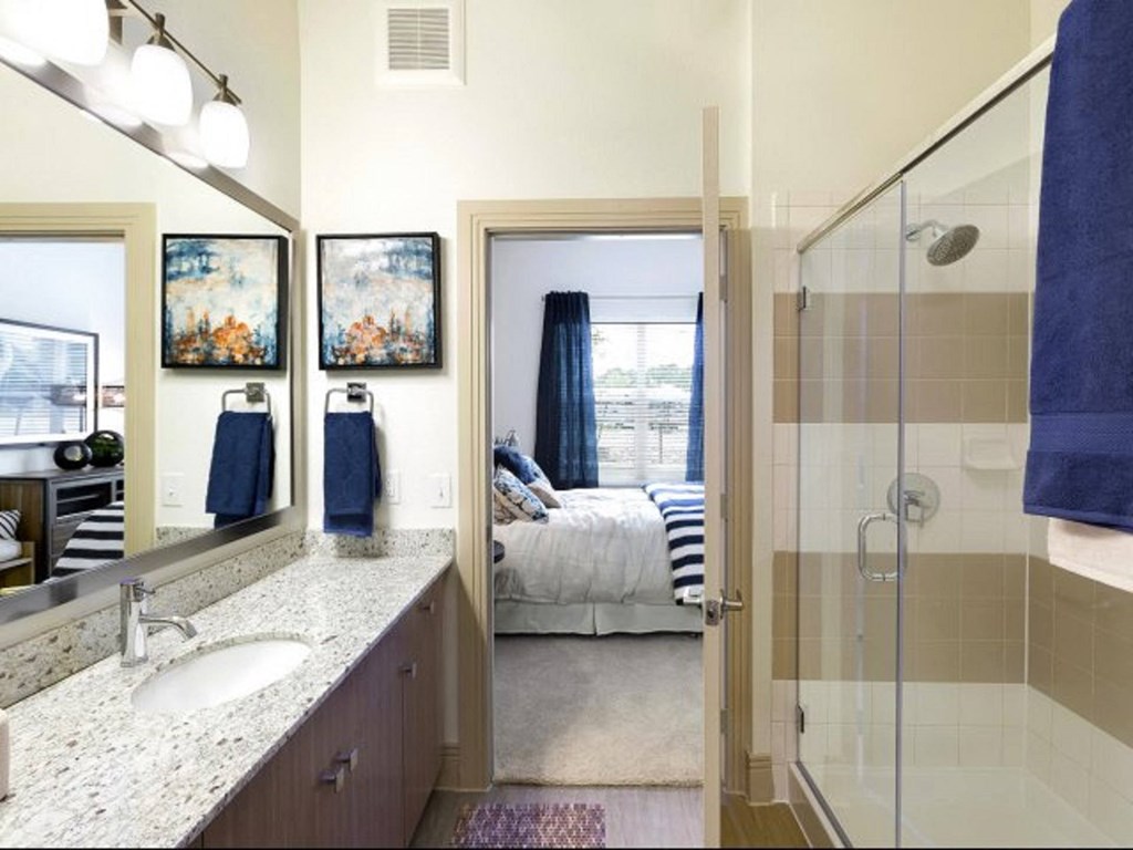 a bathroom with a shower and a sink and a bedroom