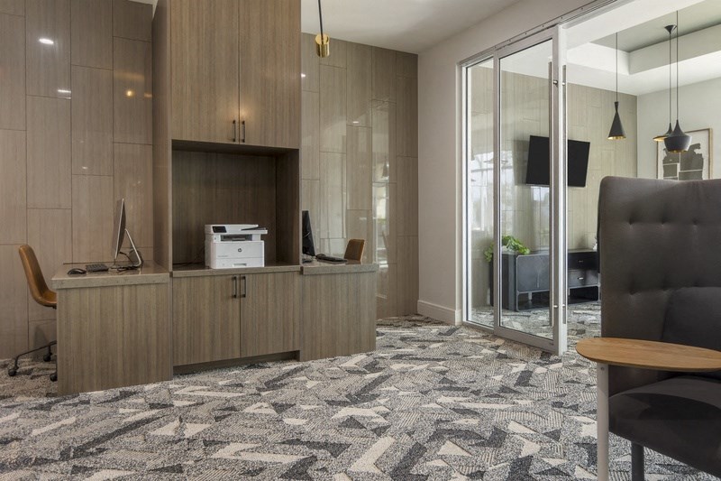 an office with a desk and a printer in a room with a glass door