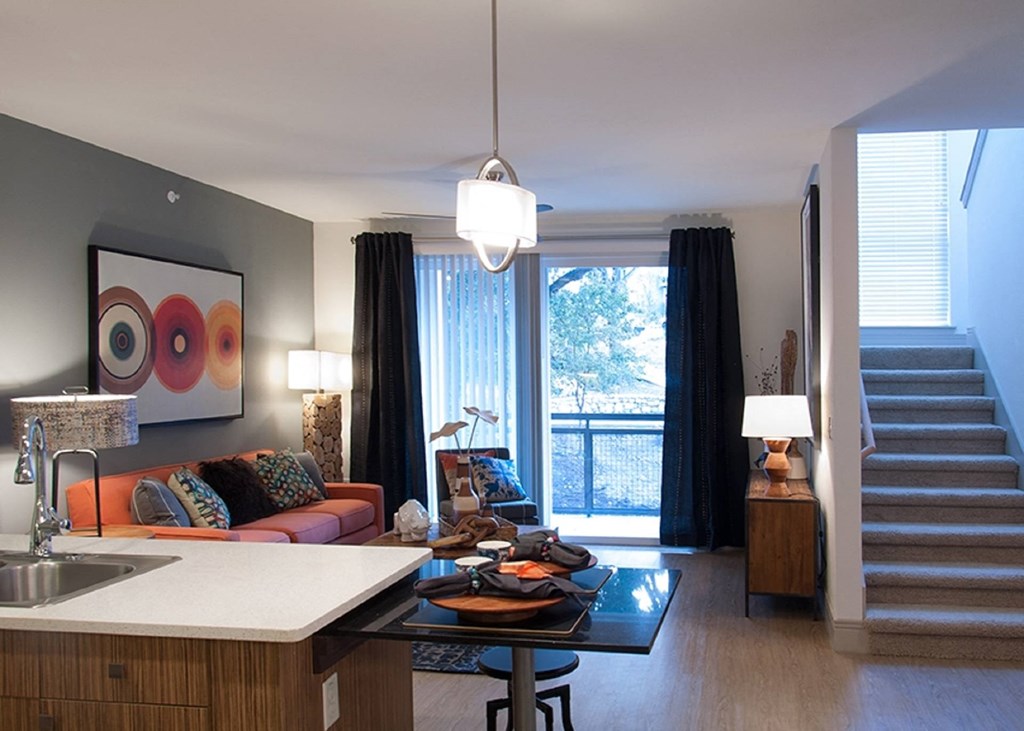 a living room with an orange couch and a kitchen and a staircase