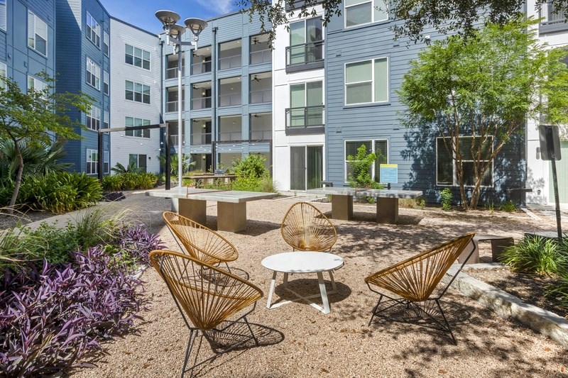a courtyard with two chairs and a table in front of an apartment building
