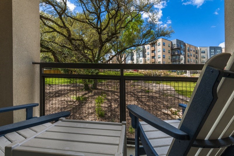 two chairs on a balcony overlooking a park with trees and buildings
