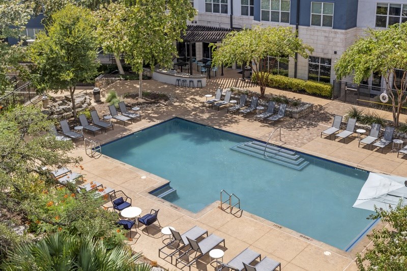 a swimming pool with chairs and a building in the background