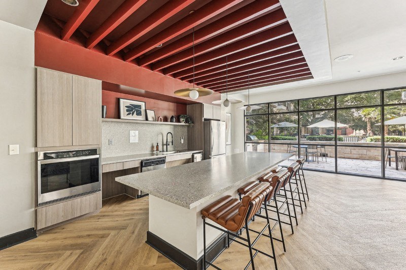 the kitchen has a large island with stools and a large window