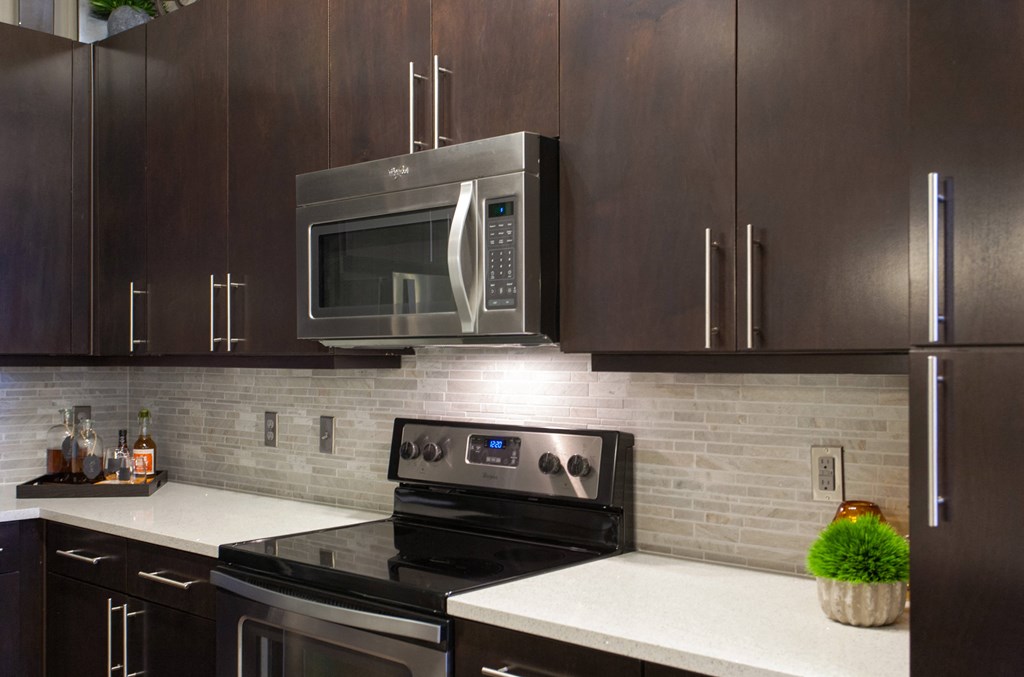 A modern kitchen with dark wood cabinets and a white countertop.