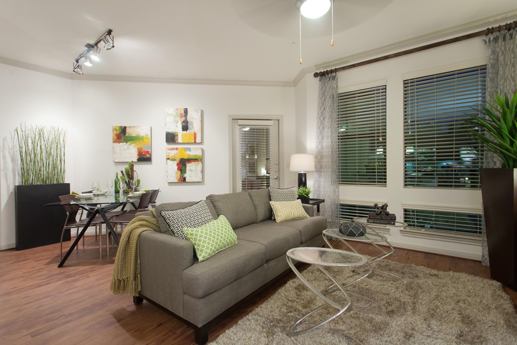 A living room with a grey couch and a glass coffee table.