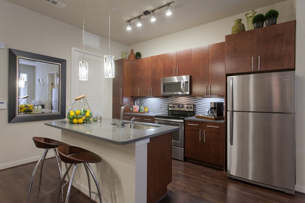 A modern kitchen with a stainless steel refrigerator and wooden cabinets.