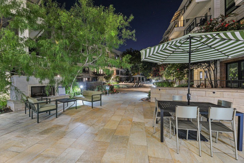 a patio with tables and chairs and an umbrella