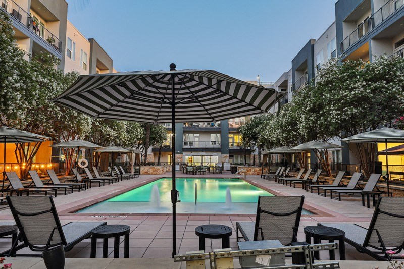a pool with chairs and umbrellas at an apartment complex