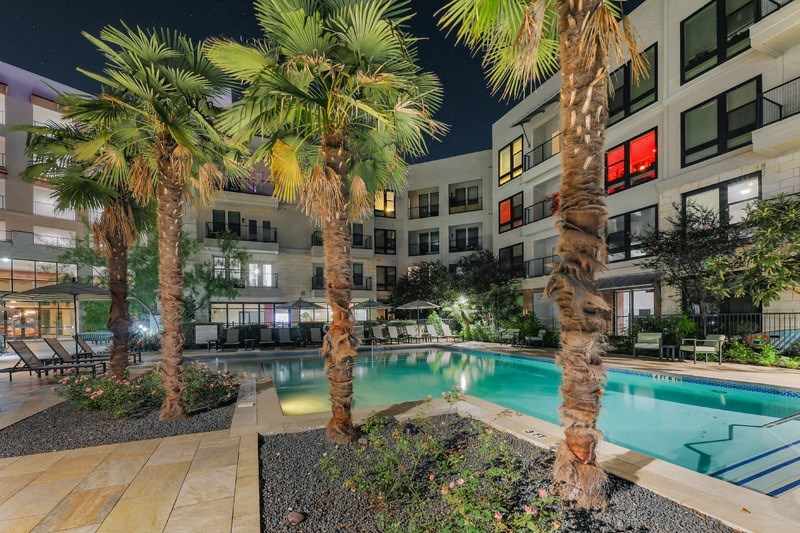 a swimming pool with palm trees in front of an apartment building