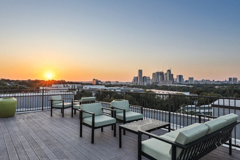 a rooftop terrace with a view of the city at sunset