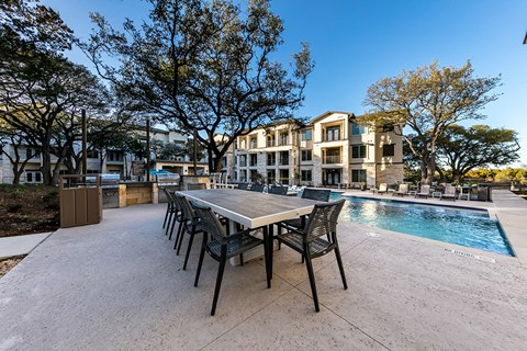 a patio with a table and chairs next to a swimming pool