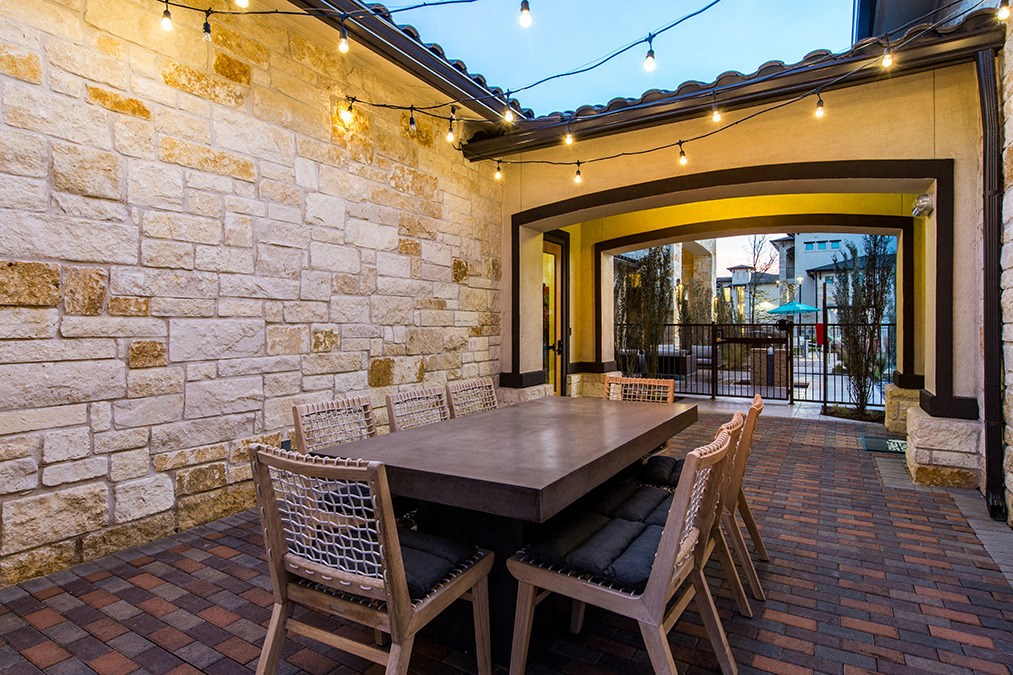 a dining area with a table and chairs under string lights