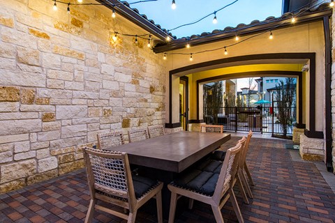 a dining area with a table and chairs under string lights