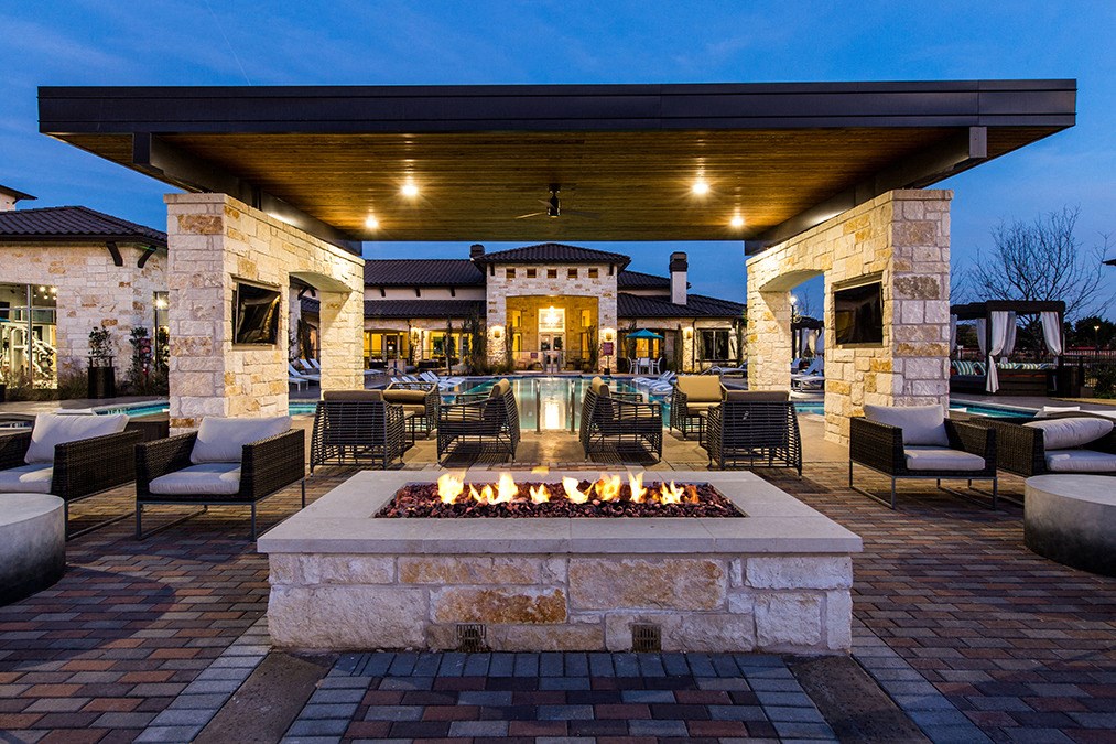 an outdoor patio with a fire pit and tables and chairs