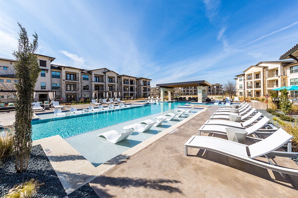 a swimming pool with lounge chairs at the resort on a sunny day