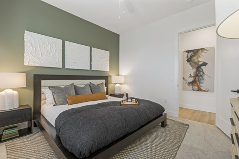 A bedroom with a large bed and a painting on the wall.