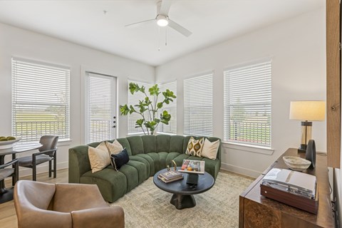 A living room with a green couch and a ceiling fan.