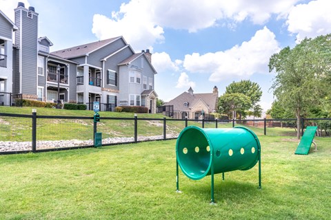 A playground with a green slide and a green tunnel-like structure in the foreground.