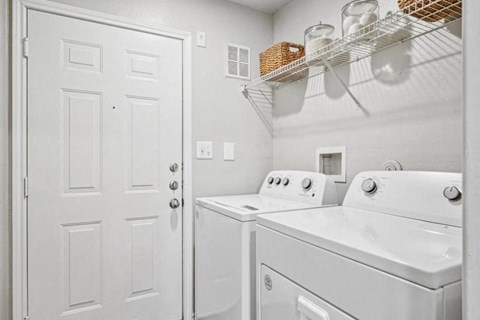 a white laundry room with white appliances and a white door