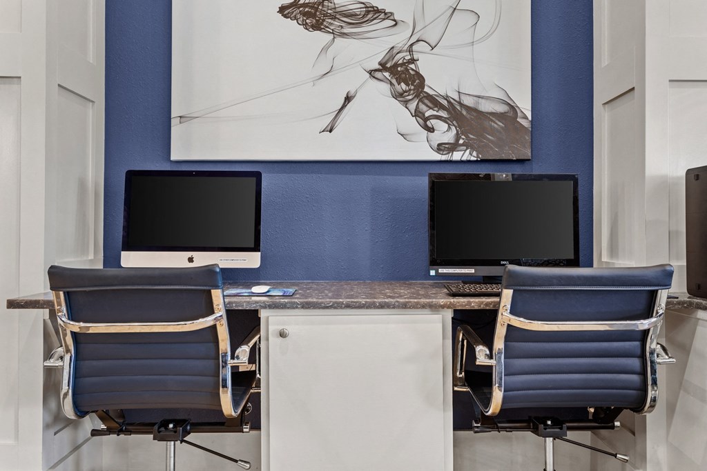 a desk with two computers and chairs in a room