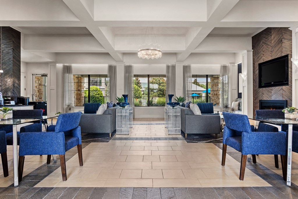 the lobby of a hotel with blue chairs and tables