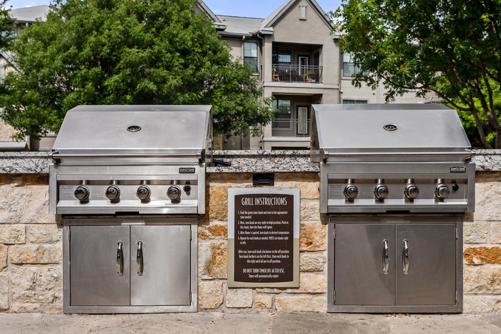 two stainless steel barbecue grills in front of a house