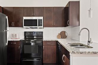 a kitchen with black appliances and brown cabinets and a sink