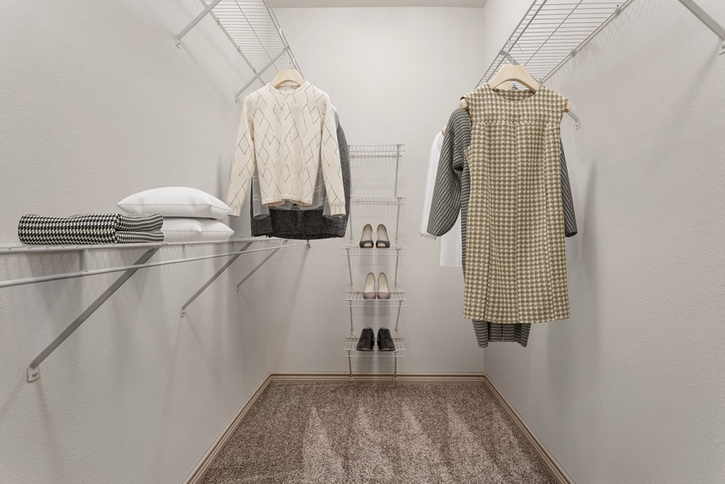 a walk in closet with clothes hanging on the wall and a glass shelf