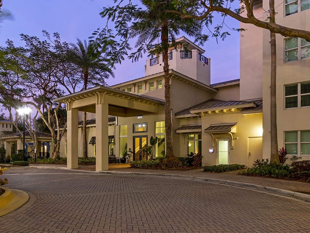 a building with a driveway and trees in front of it